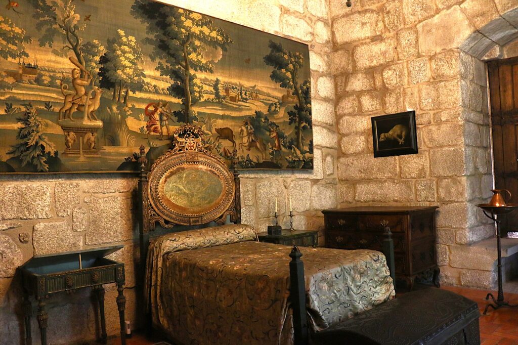Stone masonry walls typical of medieval fortifications and Antique bed with ornate headboard carved wood with gilded details.