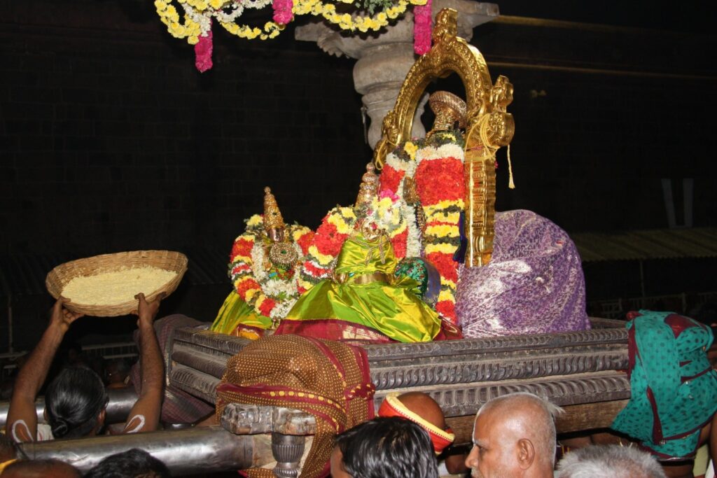 Wide-angle view of the Namperumal deity during a festival procession at Srirangam Temple, surrounded by crowds of devotees in the historic temple corridors.