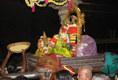 Wide-angle view of the Namperumal deity during a festival procession at Srirangam Temple, surrounded by crowds of devotees in the historic temple corridors.